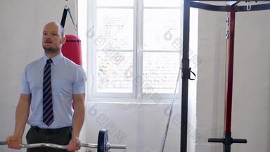 视图男人。衬衫领带提升重重量健身房男性模型完美的身体肱二头肌锻炼商人练习杠铃健身房成功的业务收入增长概念